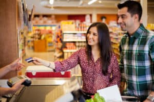 Young couple at grocery store checkout line paying with credit card